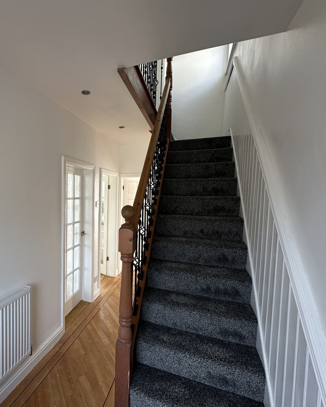 Hallway and staircase after: panelling painted white, new carpet